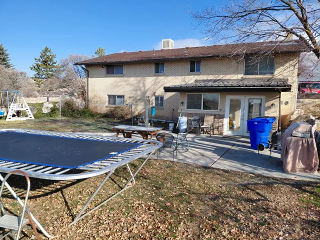 Back of property featuring a trampoline, french doors, brick siding, and a patio