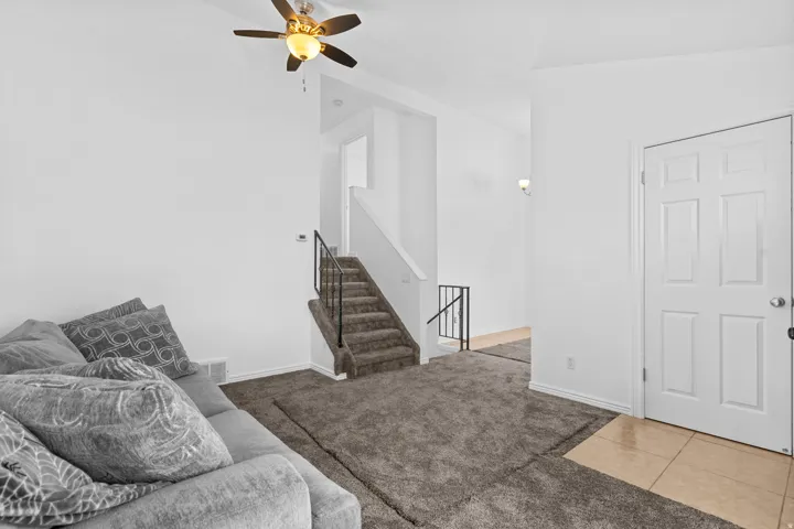 Carpeted living area with ceiling fan and tile patterned floors
