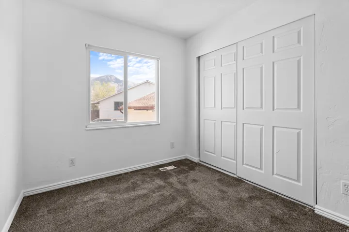 Unfurnished bedroom featuring dark colored carpet, a closet, and a textured wall