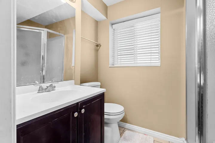 Bathroom featuring vanity, light tile patterned floors, and a shower stall