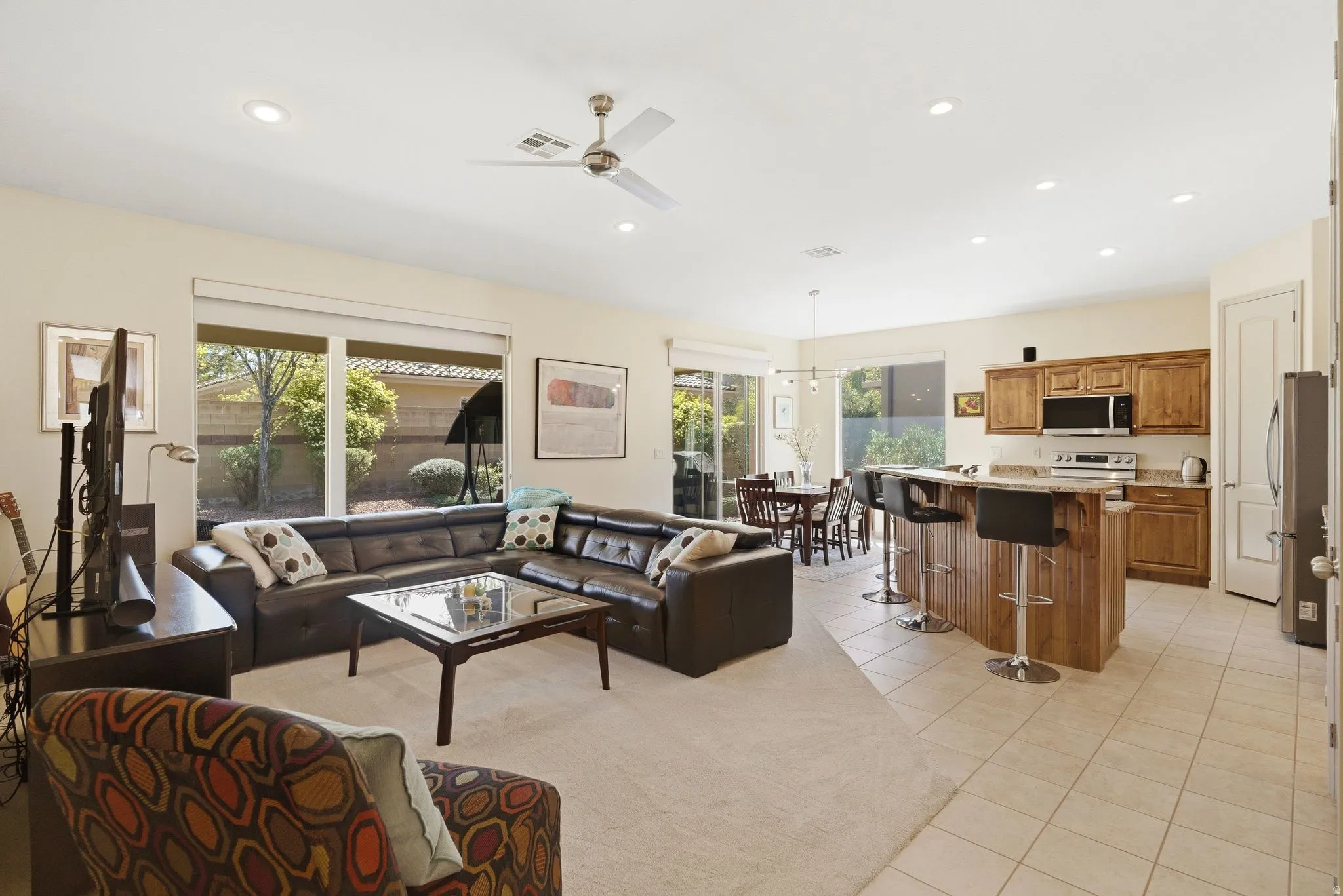 Living room featuring a ceiling fan, light tile patterned flooring, and a chandelier