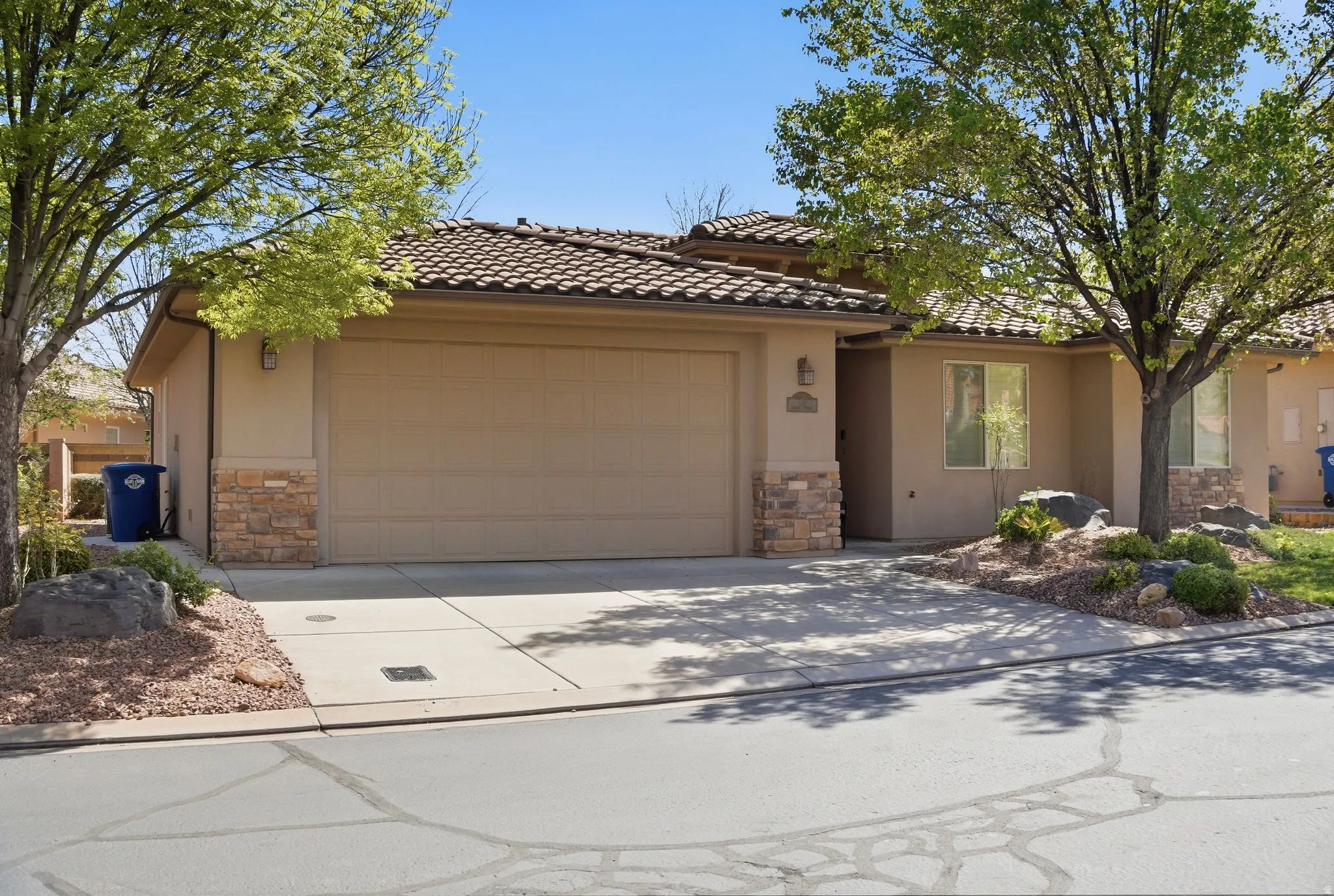 View of front of home featuring stone siding, an attached garage, stucco siding, concrete driveway, and a tiled roof