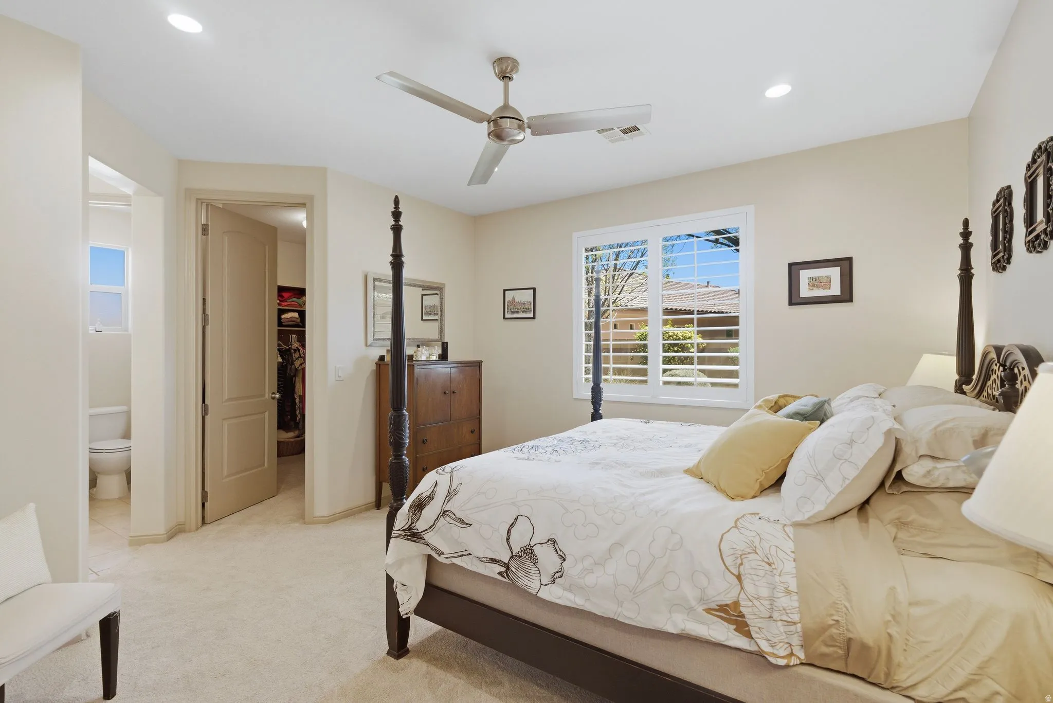 Bedroom featuring a spacious closet, ceiling fan, light colored carpet, recessed lighting, and ensuite bath