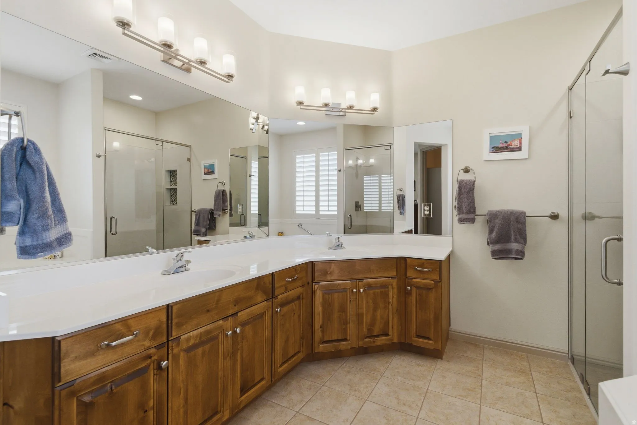 Full bathroom featuring double vanity, a stall shower, and light tile patterned floors