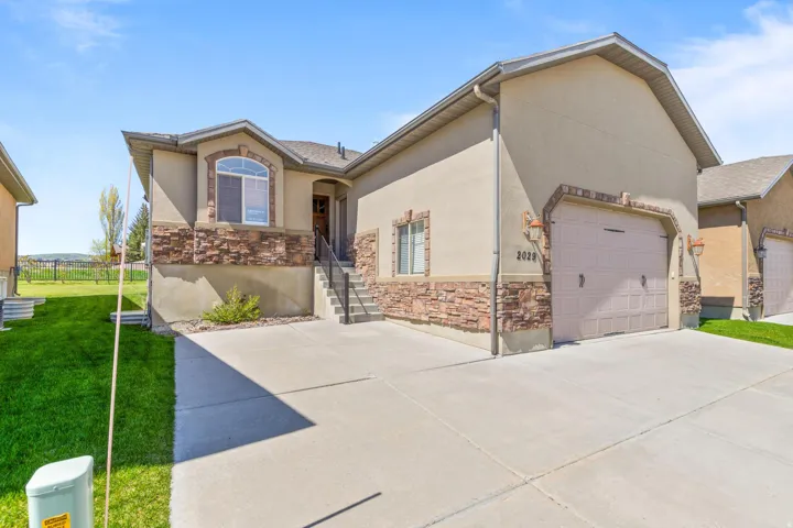 View of front of home featuring an attached garage, stone siding, stucco siding, and concrete driveway