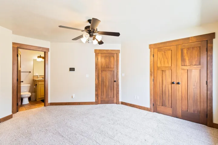 Unfurnished bedroom featuring carpet floors, a ceiling fan, ensuite bathroom, and a closet