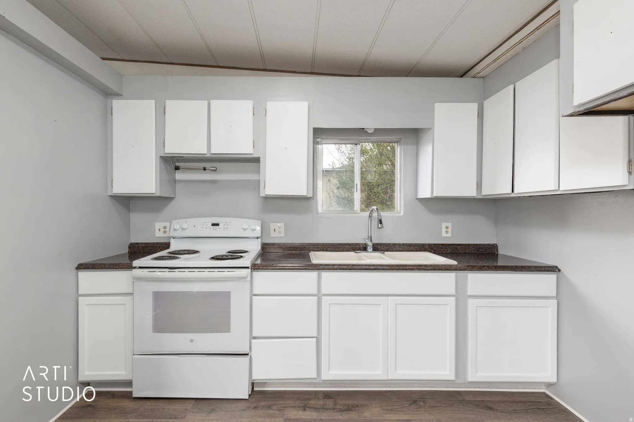 Kitchen with white electric stove, white cabinetry, dark countertops, and dark wood-style flooring