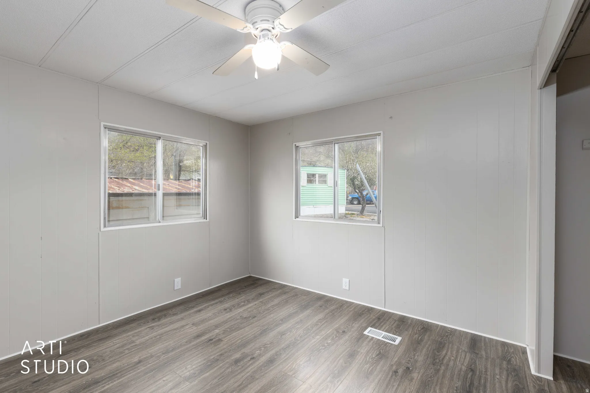 Spare room featuring dark wood-style flooring, ceiling fan, and wood walls