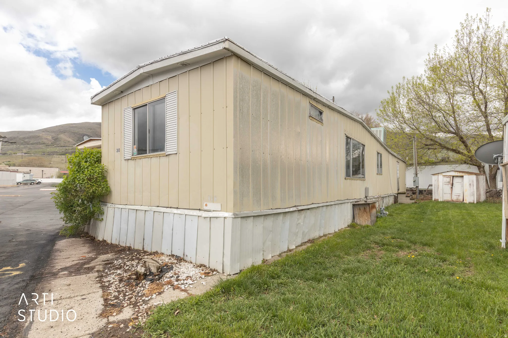View of side of property with a storage unit, a lawn, and a mountain view