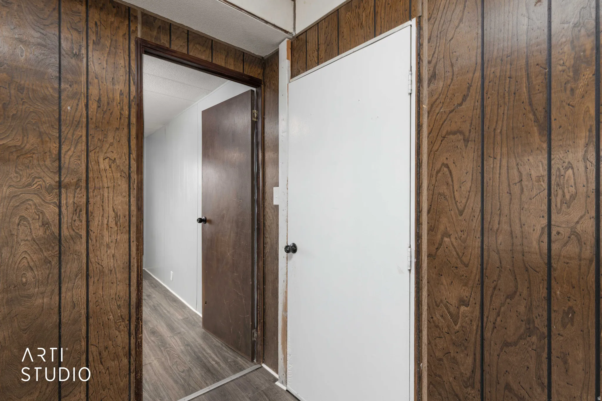 Hallway featuring dark wood-type flooring and wood walls