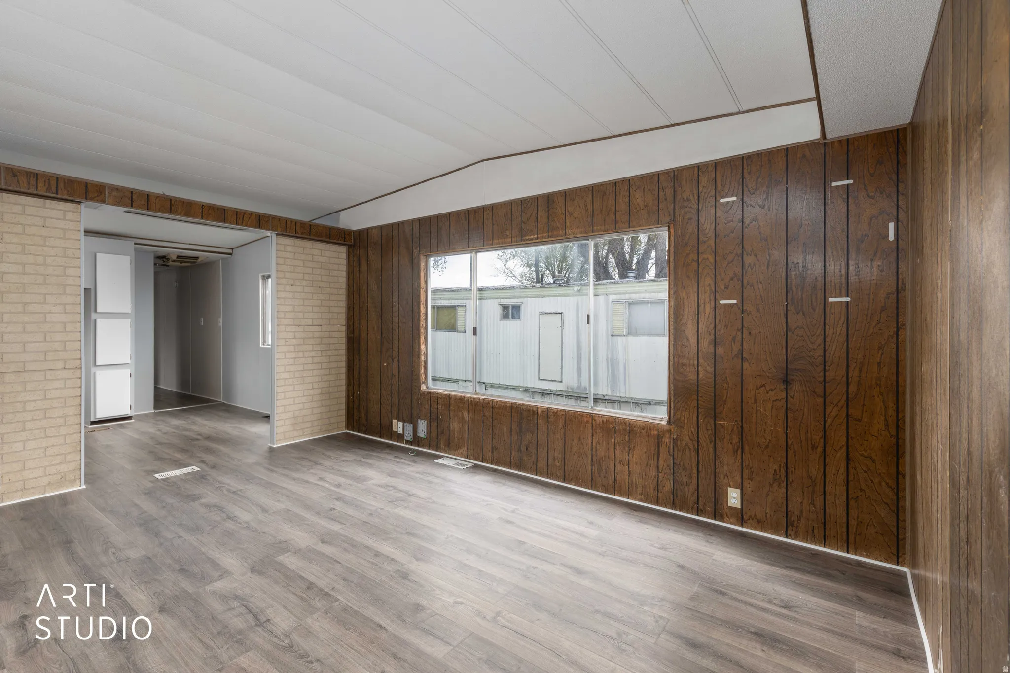 Spare room with vaulted ceiling, wood finished floors, and wooden walls
