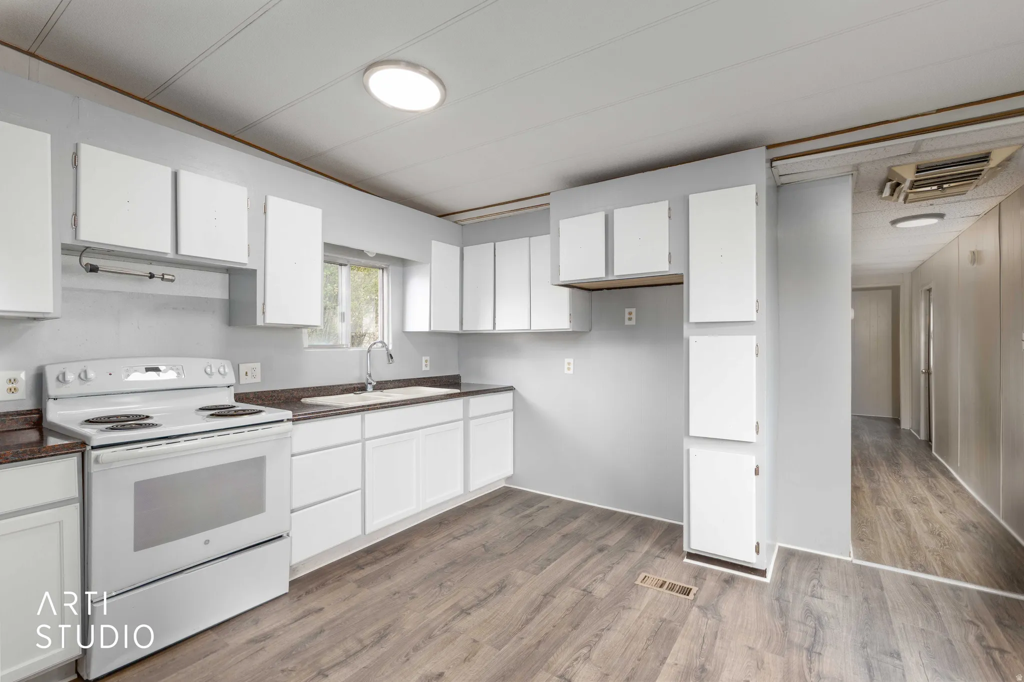 Kitchen featuring white cabinets, white range with electric cooktop, dark countertops, cooling unit, and dark wood finished floors