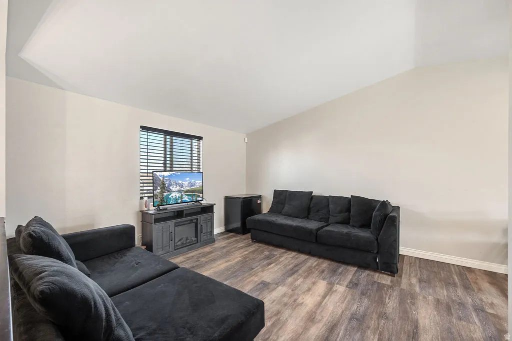 Living area featuring vaulted ceiling and dark wood-style floors