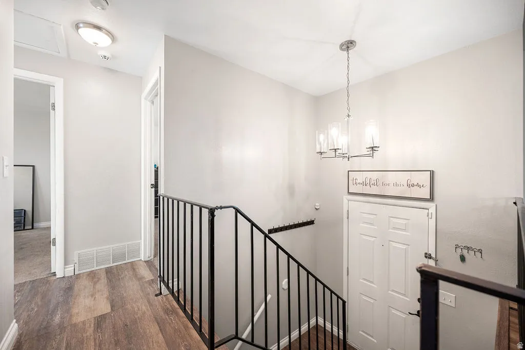 Staircase with wood finished floors and suspended lighting