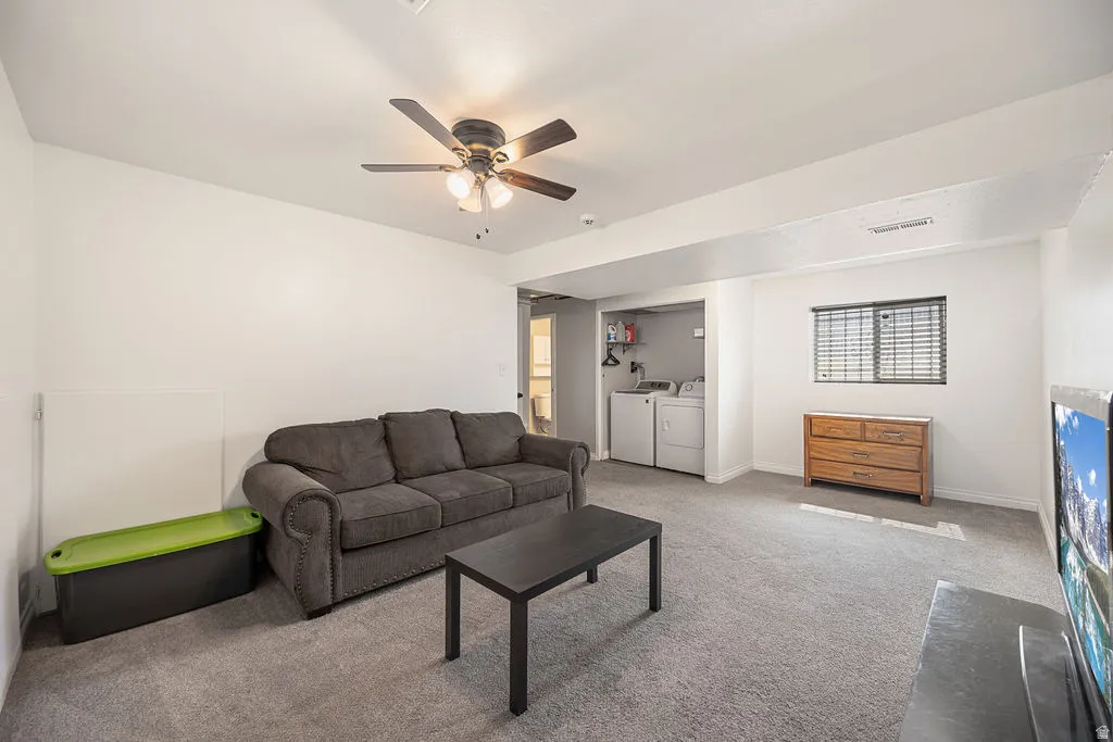 Carpeted living area with a ceiling fan and washing machine and clothes dryer