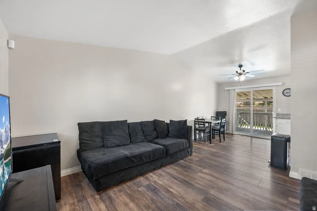 Living area featuring dark wood finished floors, lofted ceiling, and a ceiling fan