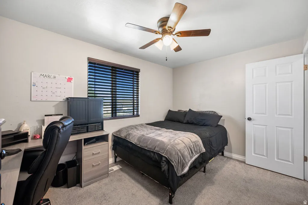 Bedroom with light colored carpet, a desk, and ceiling fan