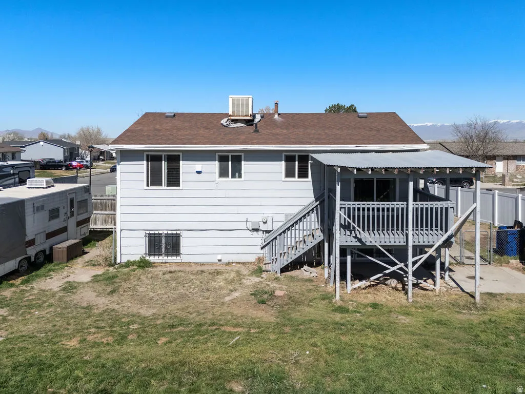 Back of house with a wooden deck and roof with shingles
