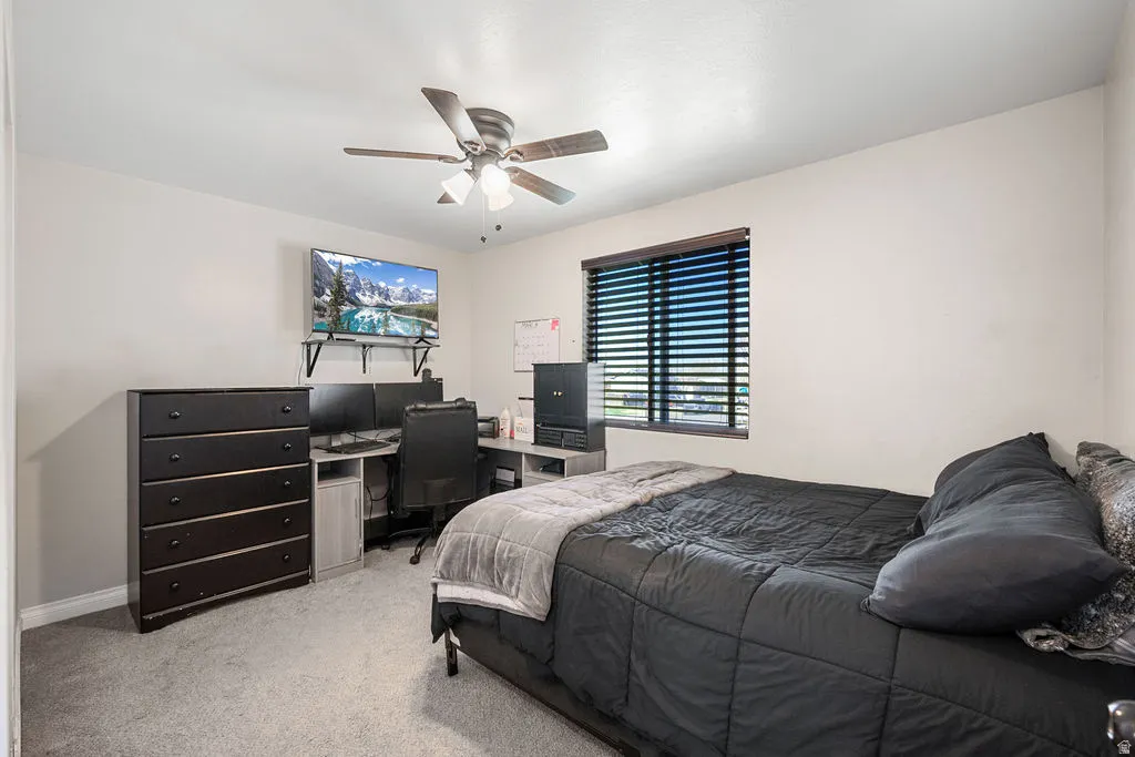 Carpeted bedroom with an office area and a ceiling fan