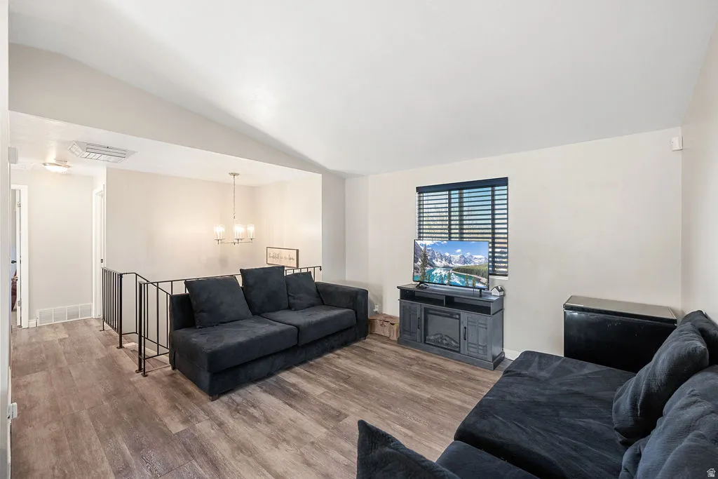 Living area featuring lofted ceiling, wood finished floors, and hanging lights