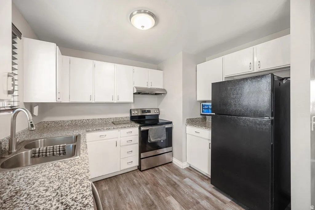 Kitchen featuring freestanding refrigerator, stainless steel electric stove, and white cabinetry