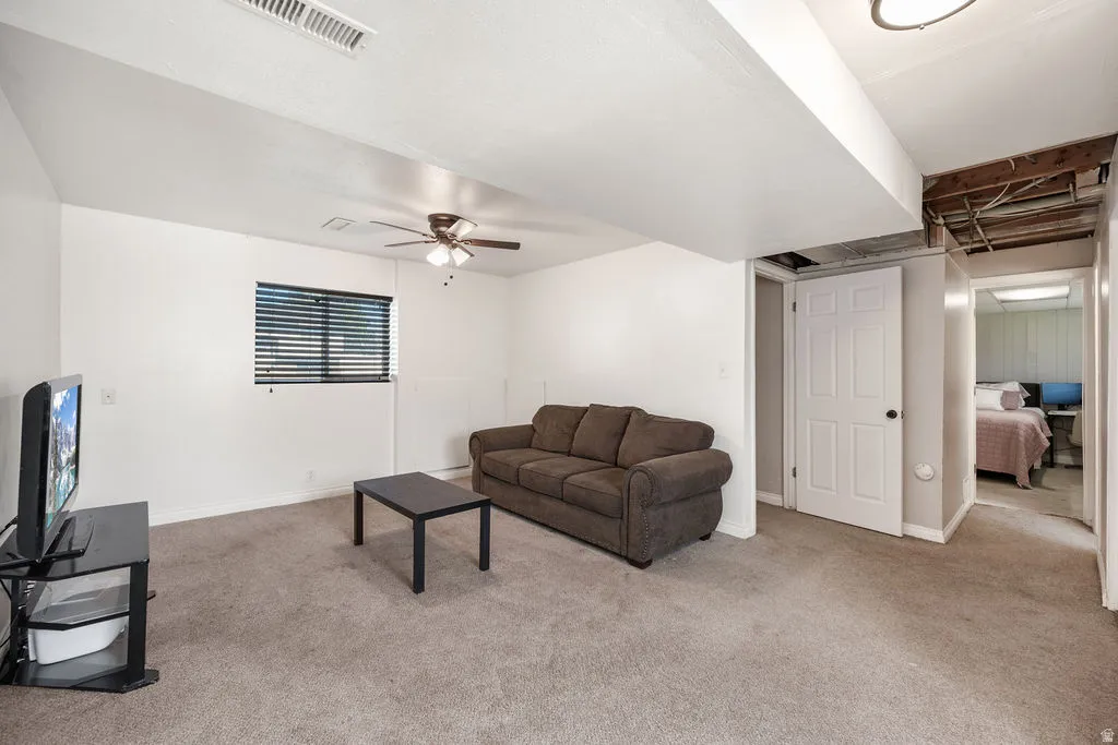 Living area featuring light carpet and ceiling fan