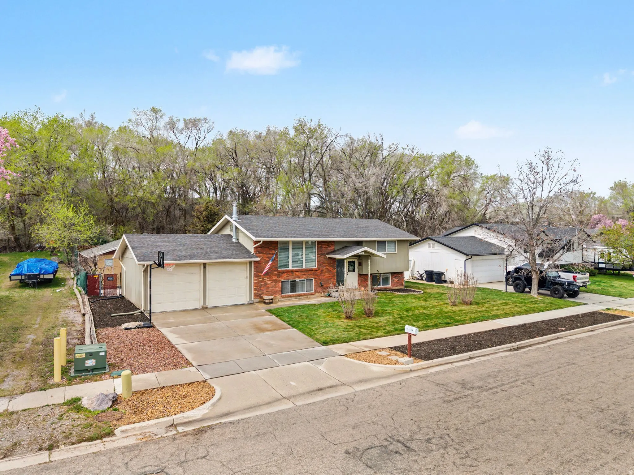 Bi-level home featuring brick siding, driveway, a garage, a front lawn, and a shingled roof