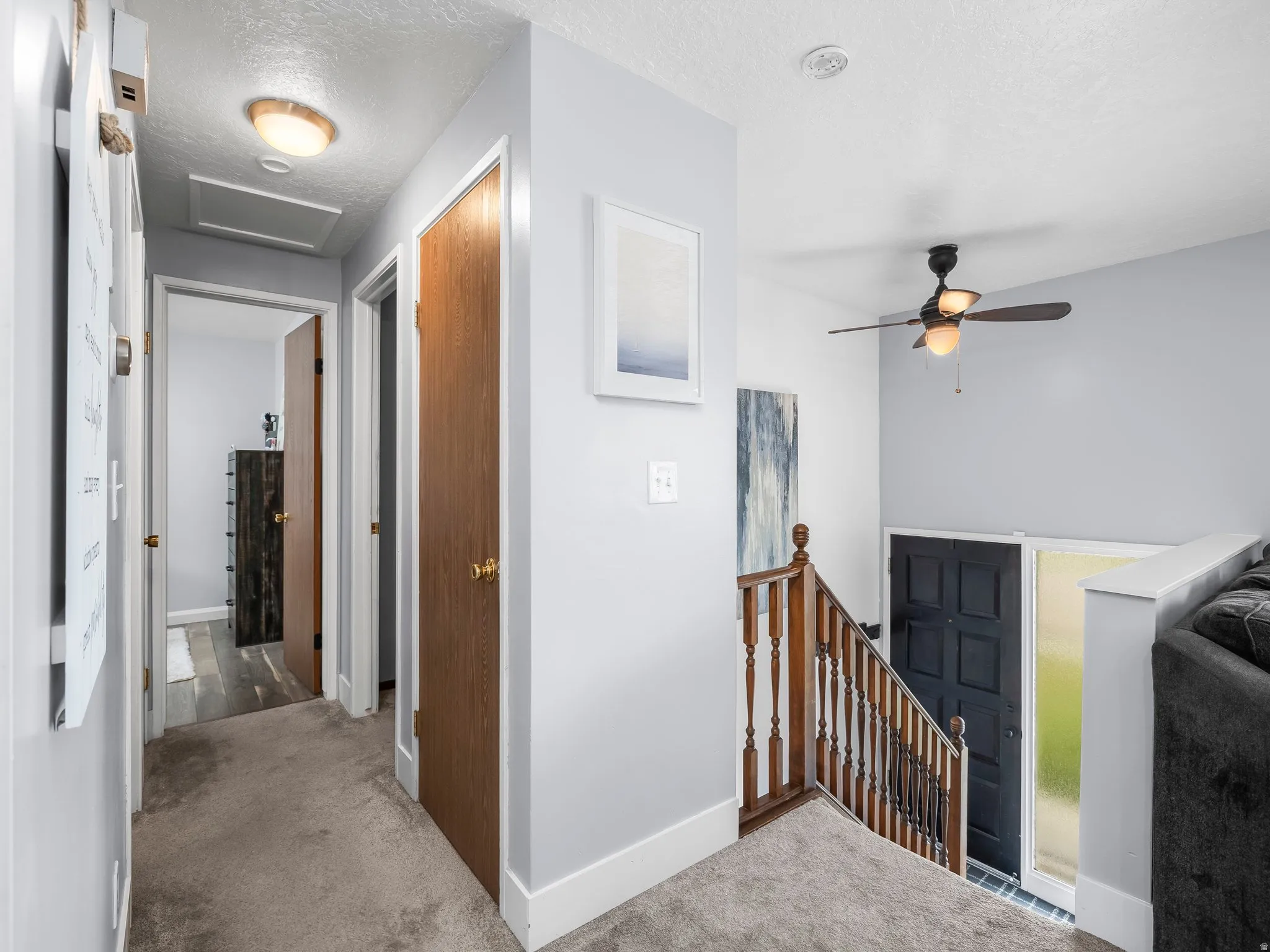 Hallway with carpet floors, an upstairs landing, and a textured ceiling