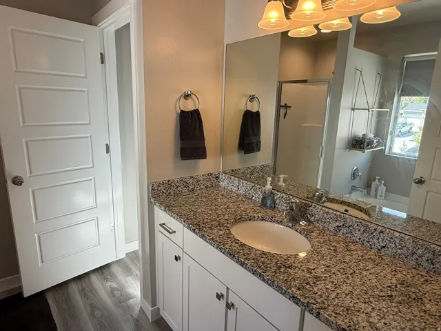 Bathroom with a shower stall, vanity, dark wood-style flooring, and a bath