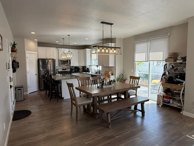 Dining room with dark wood finished floors, a textured ceiling, and recessed lighting