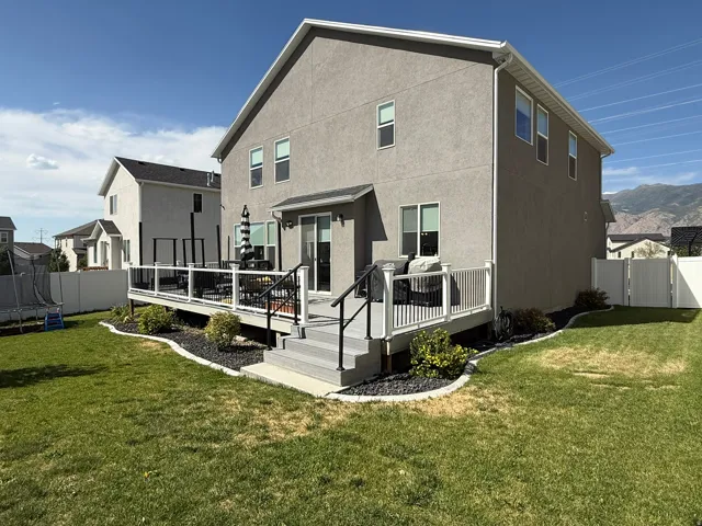 Back of house featuring a fenced backyard, a deck with mountain view, a trampoline, a gate, and stucco siding