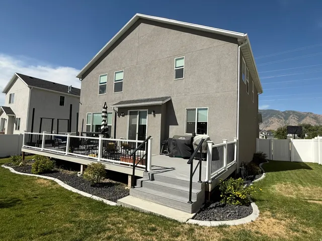 Back of property with a deck with mountain view and stucco siding