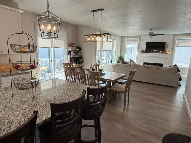 Dining space with healthy amount of natural light, dark wood finished floors, a fireplace, a textured ceiling, and ceiling fan
