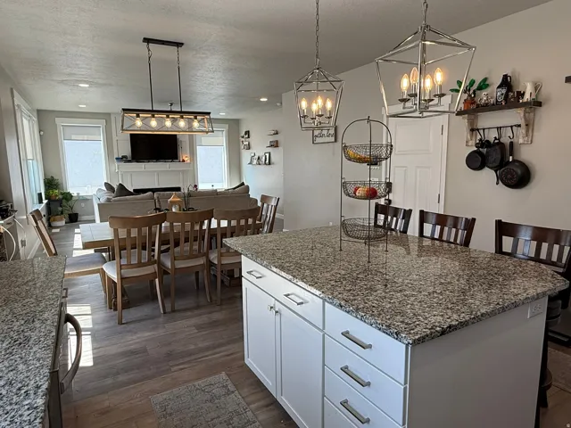 Kitchen with white cabinetry, a breakfast bar area, dark stone countertops, a kitchen island, and a textured ceiling