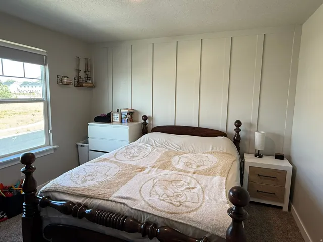 Bedroom featuring dark colored carpet and a textured ceiling