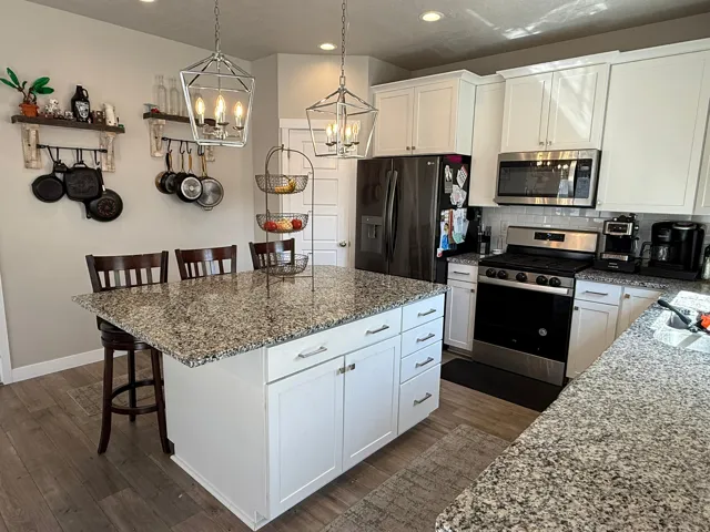 Kitchen featuring white cabinetry, a kitchen breakfast bar, light stone counters, tasteful backsplash, and stainless steel appliances