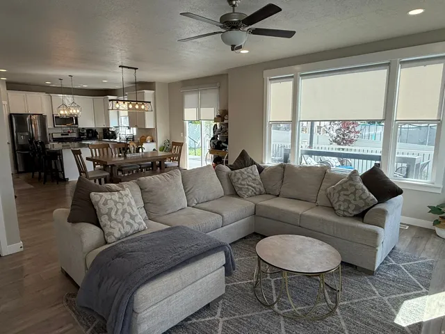 Living room featuring dark wood-type flooring, recessed lighting, a ceiling fan, and a textured ceiling