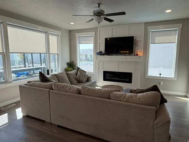 Living room featuring a fireplace, dark wood finished floors, a ceiling fan, a textured ceiling, and recessed lighting