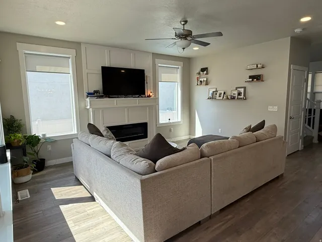 Living room with a ceiling fan, a glass covered fireplace, recessed lighting, and hardwood / wood-style flooring