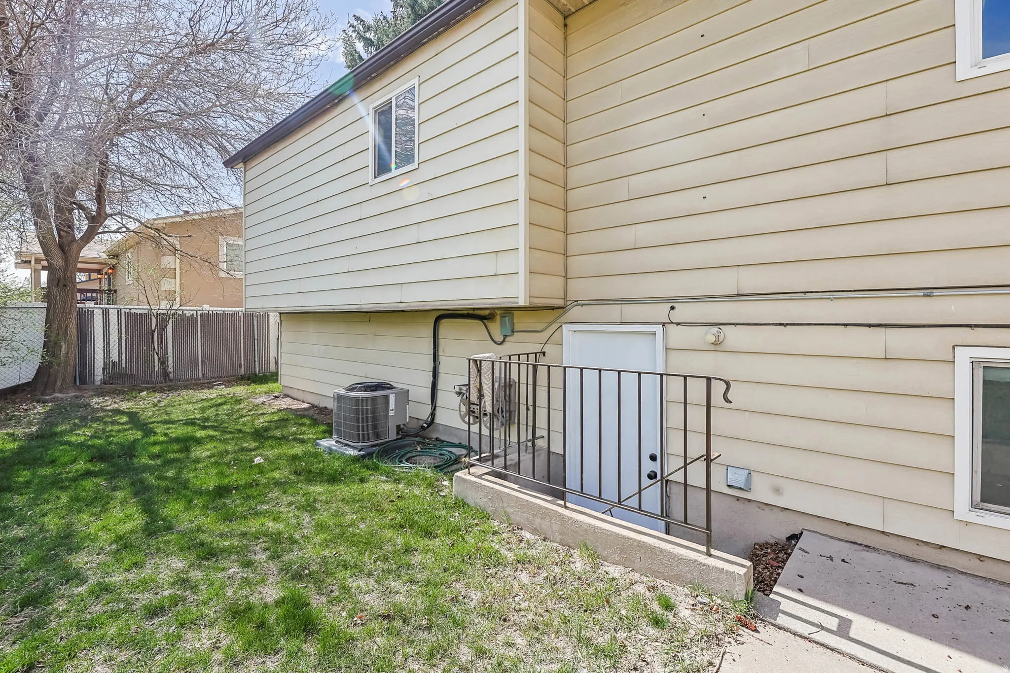 Rear exterior featuring horizontal siding, a lower-level access door with wrought iron railing, and a ground-level window
