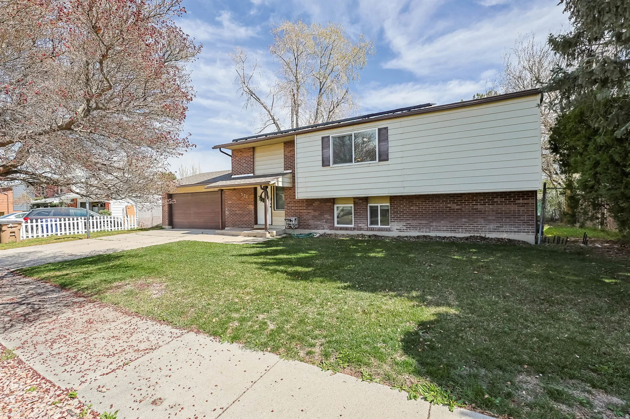 Split-level residence featuring a brick and siding exterior, an attached two-car garage, and a concrete driveway
