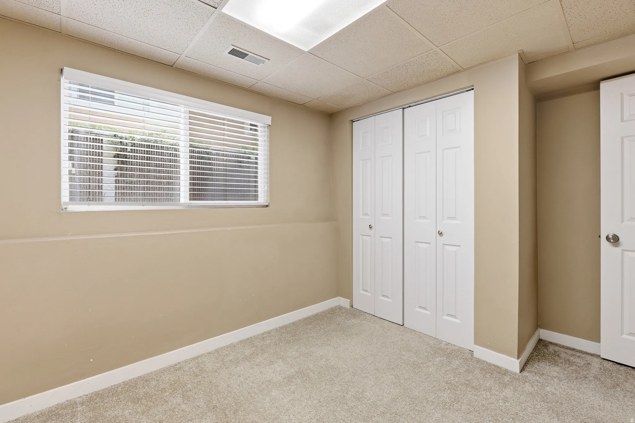 Carpeted room featuring a window with blinds, bi-fold closet doors, and recessed lighting