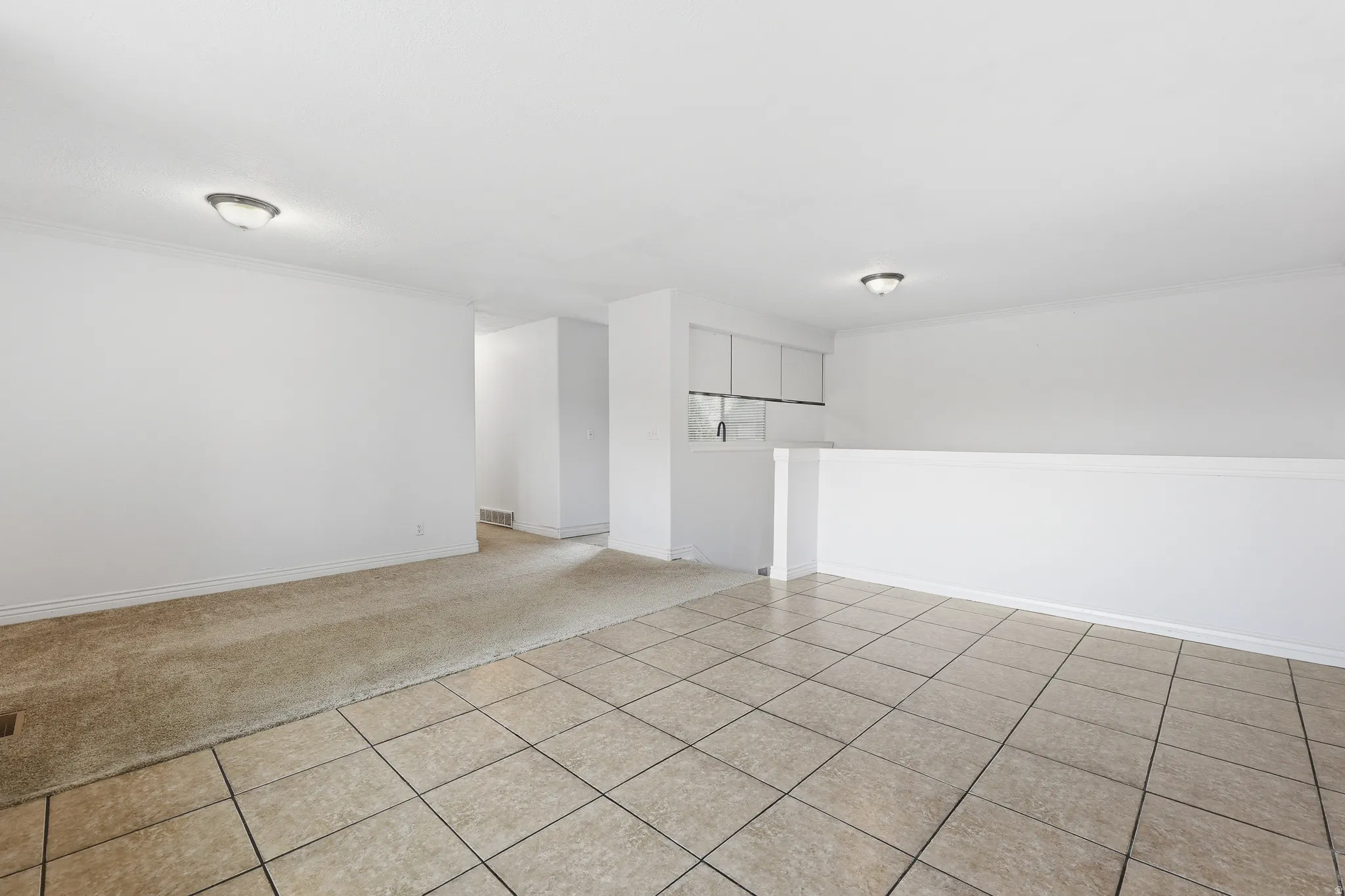 Spacious interior featuring a tiled flooring area, carpeted flooring area, and a half-wall partition