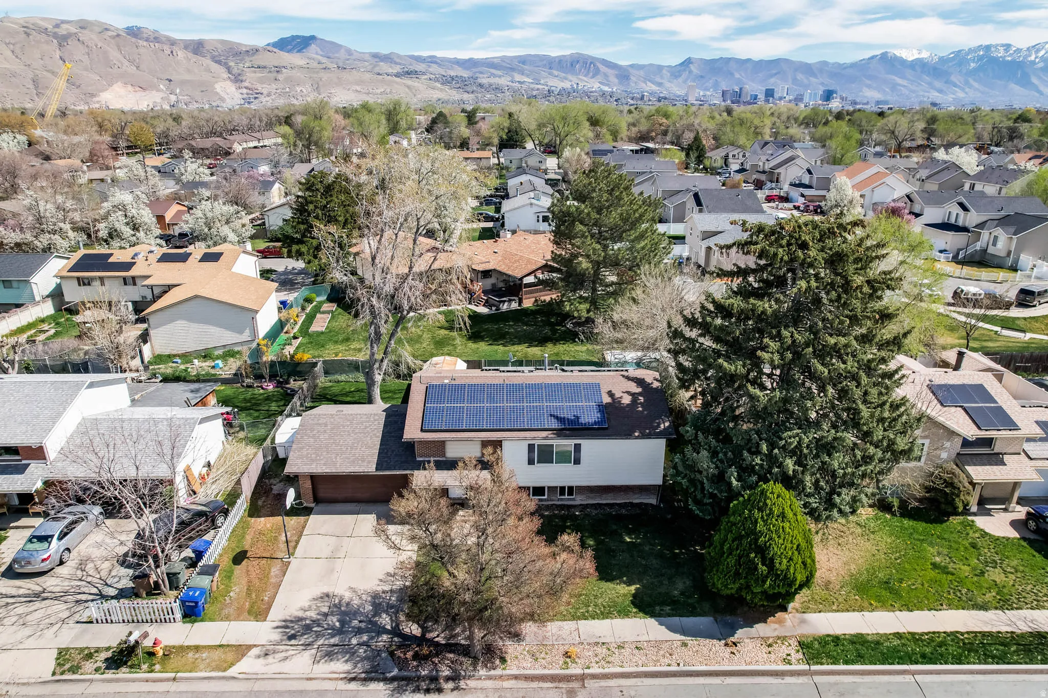 Single-story residence featuring solar panels, an attached garage, and a paved driveway