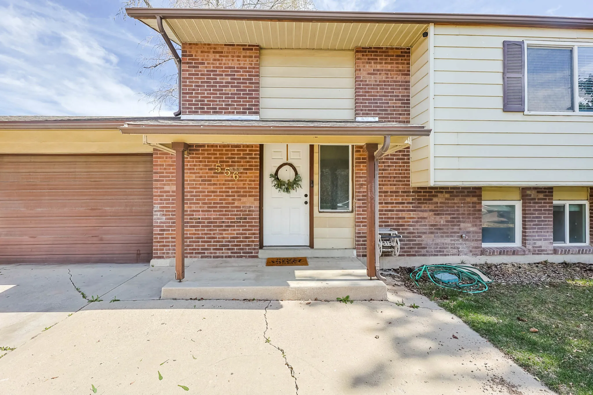 Front elevation showcasing a split-level design with brick and siding facade
