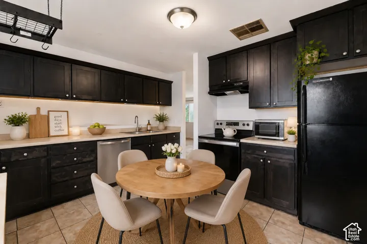 Kitchen featuring dark cabinetry, light countertops, stainless steel appliances, and tile flooring