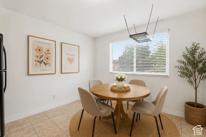 Dining area featuring tile flooring, a large window with blinds, and a built-in ceiling light fixture