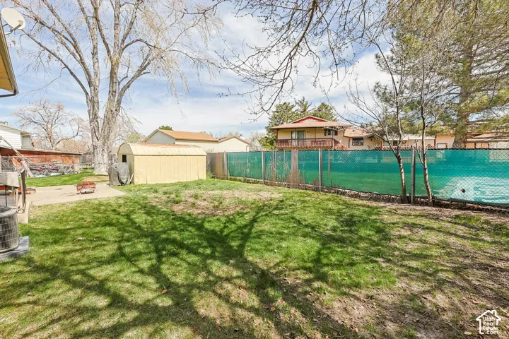 Expansive lawn with a chain-link fence, mature trees, and a concrete patio