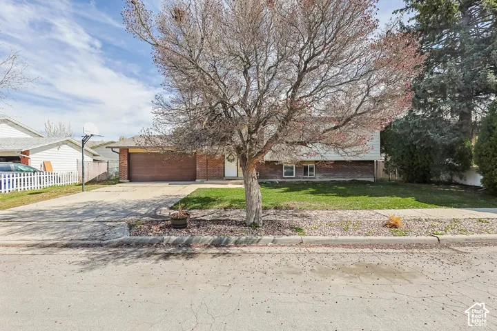 Obstructed view of property featuring brick siding, driveway, and an attached garage