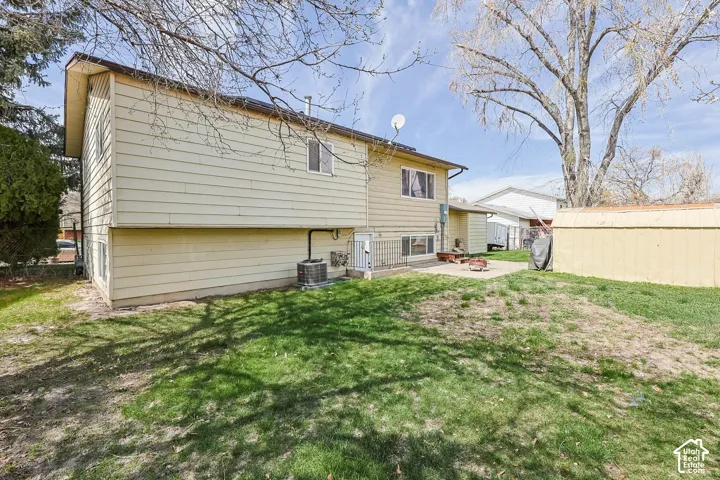 Spacious rear yard featuring a large patio, lush green lawn, and a storage shed